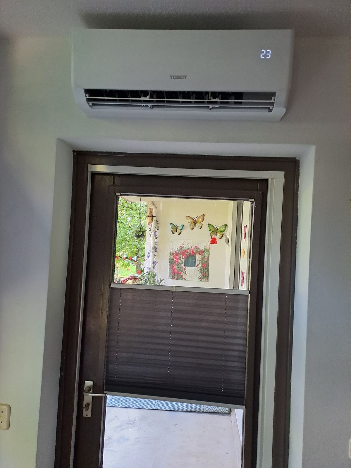 Binnenunit boven een deur, het display staat op 23 graden
