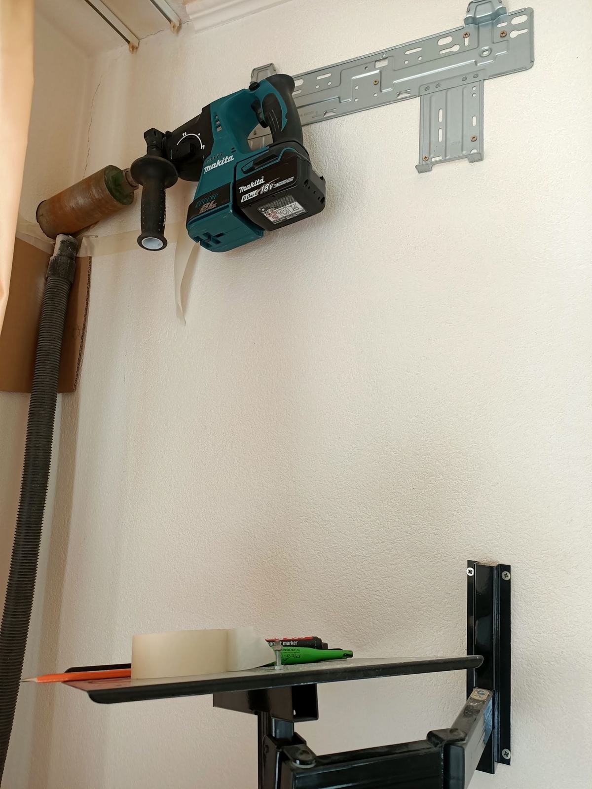 Montage in uitvoering: de montageplaat van een binnenunit op een witte muur, met een Makita-boor met stofafzuiging